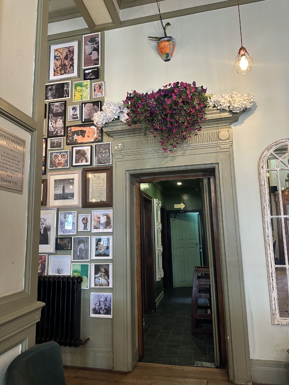 Curated art gallery wall and hanging flowers in the entrance